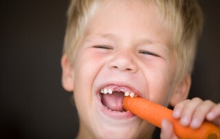 Young boy eating a carrot