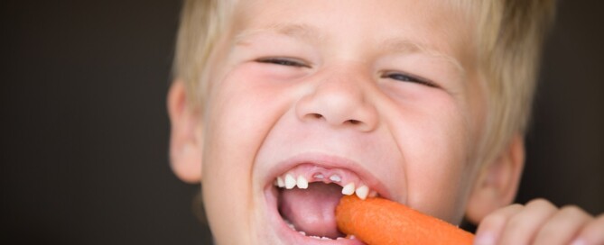 Young boy eating a carrot