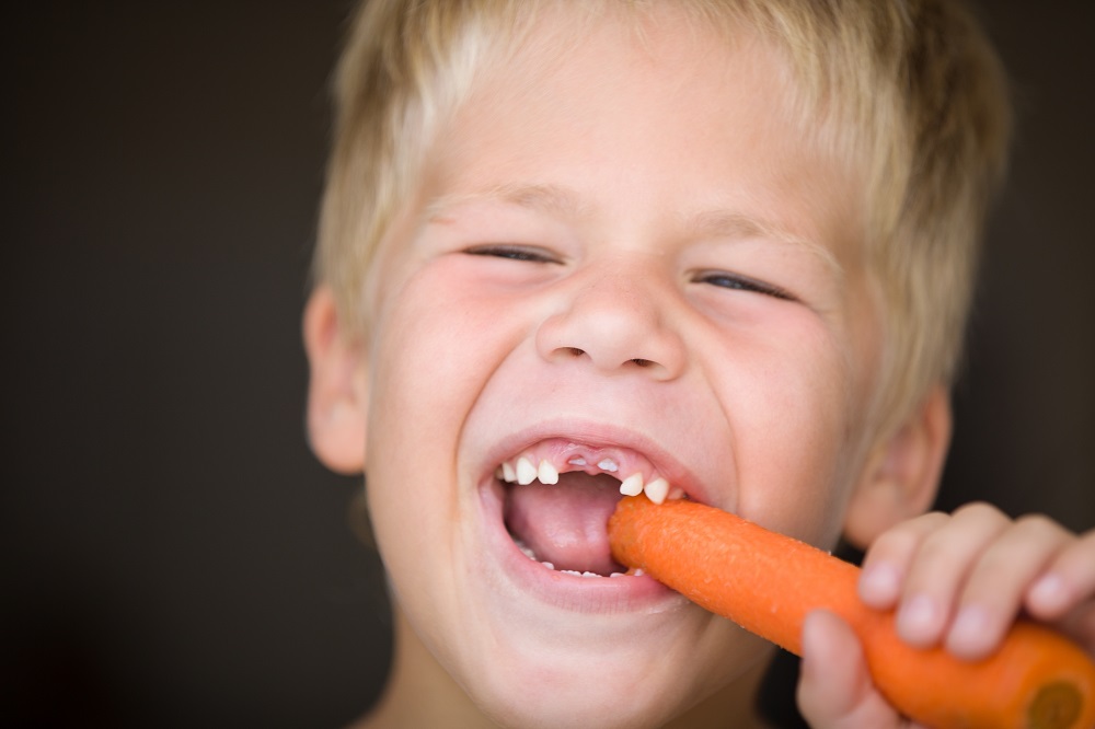 Young boy eating a carrot